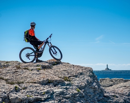 Mountain biker standing on a rocky outcrop by the sea